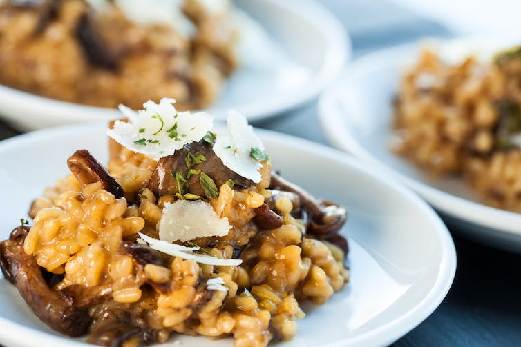 Primer plano de un risotto de champiñones dorados con escamas de parmesano encima